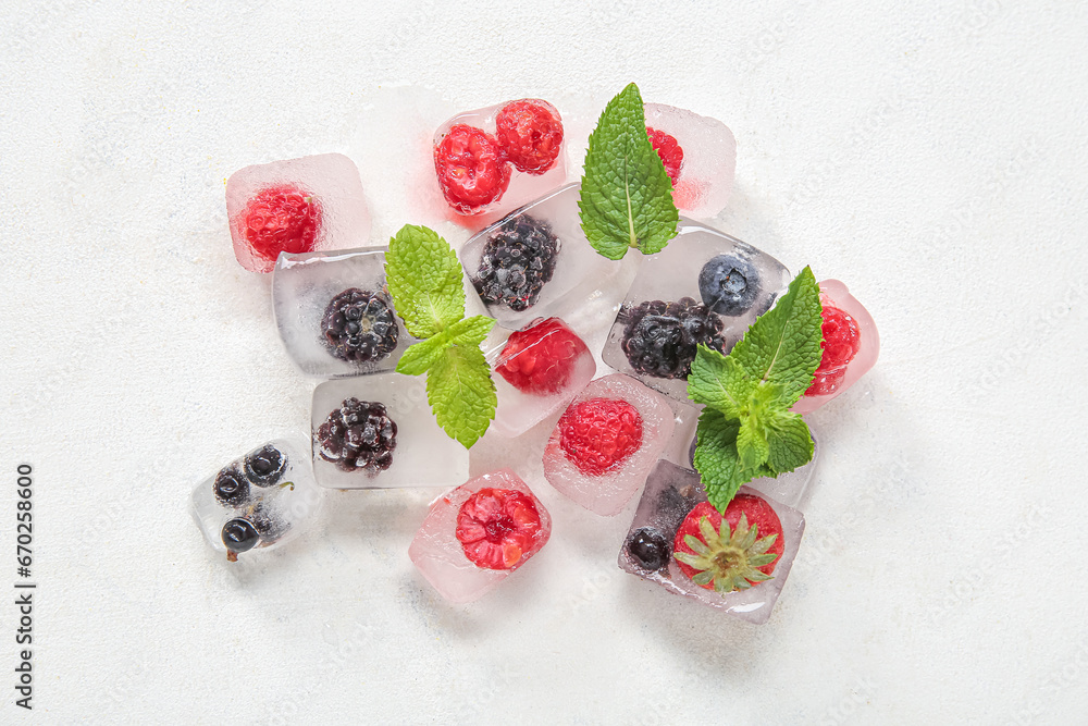 Frozen berries in ice cubes and mint on white background