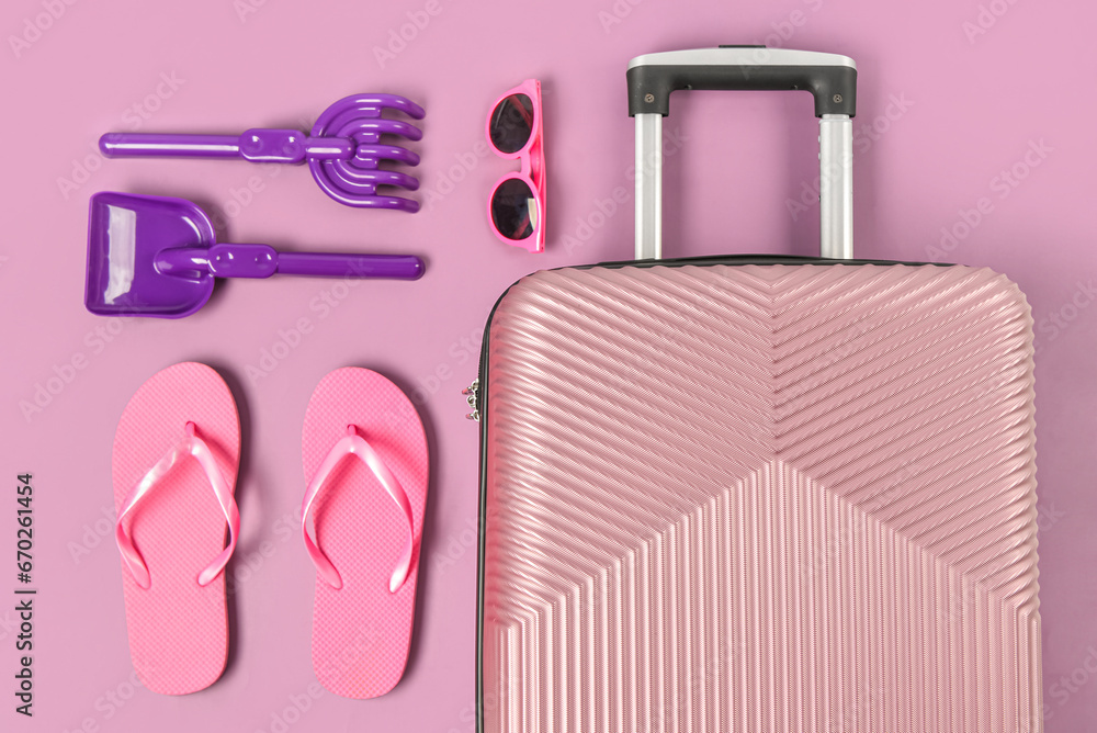 Composition with suitcase, beach accessories and toys on color background