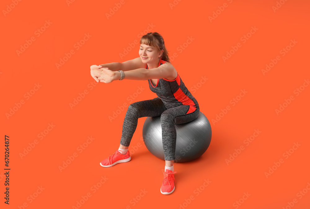 Young sporty woman training with fitness balls on red background