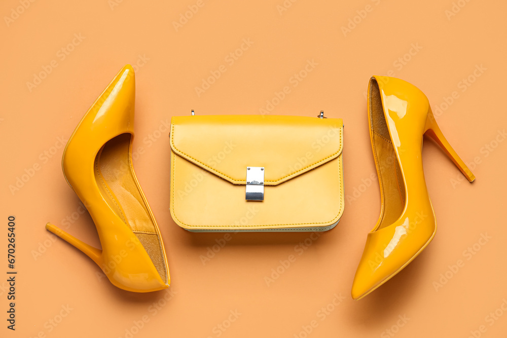 Stylish yellow high heels and purse on brown background