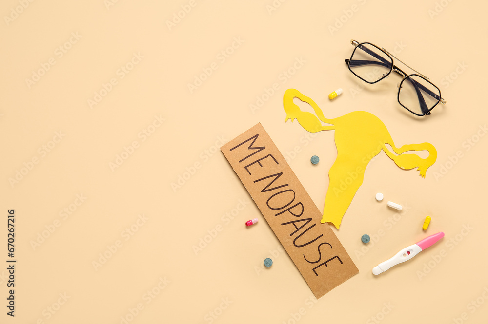 Word MENOPAUSE with paper uterus, pills, pregnancy test and eyeglasses on beige background