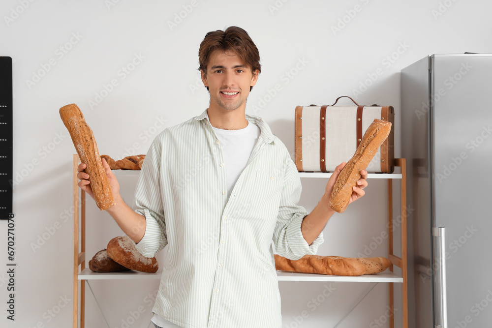 Handsome young man with loaves of fresh bread in bakery