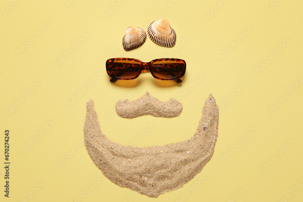 Funny face made of sand and stylish sunglasses on color background