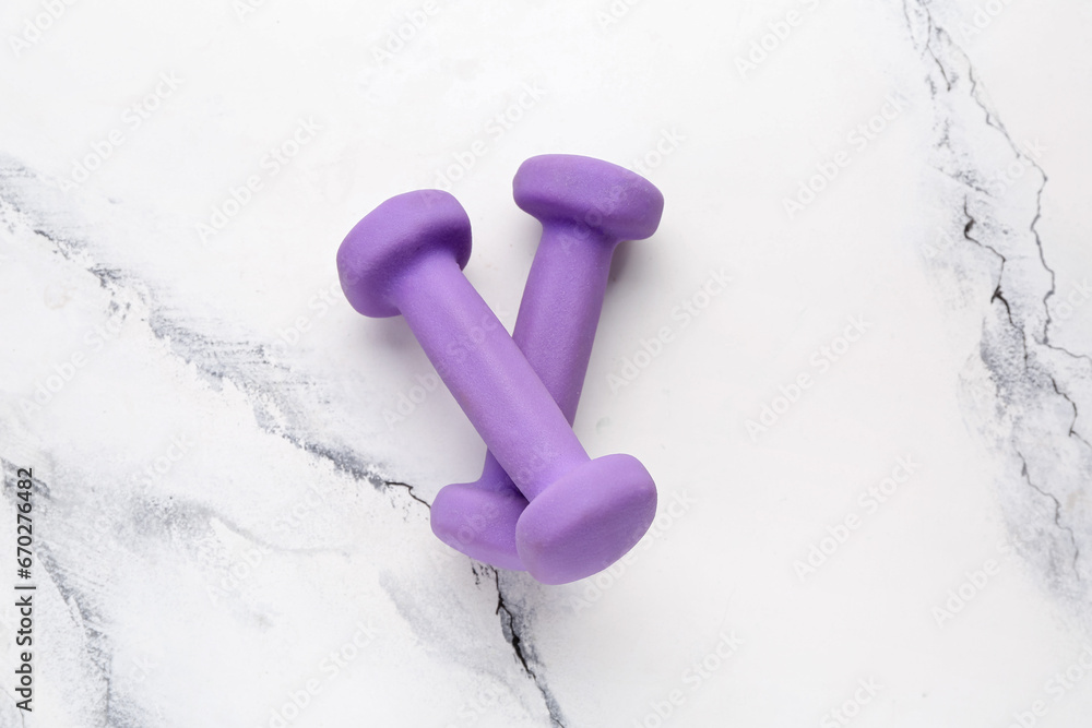 Purple dumbbells on white marble background