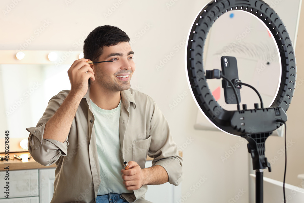 Male beauty blogger with mascara recording video in makeup room