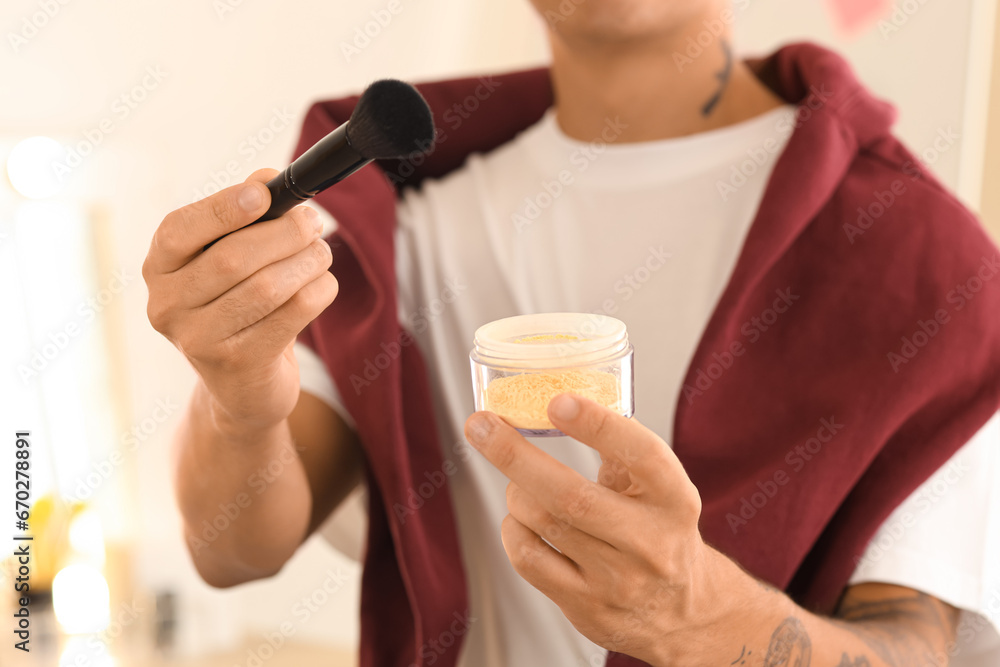 Male beauty blogger with brush and powder in makeup room, closeup