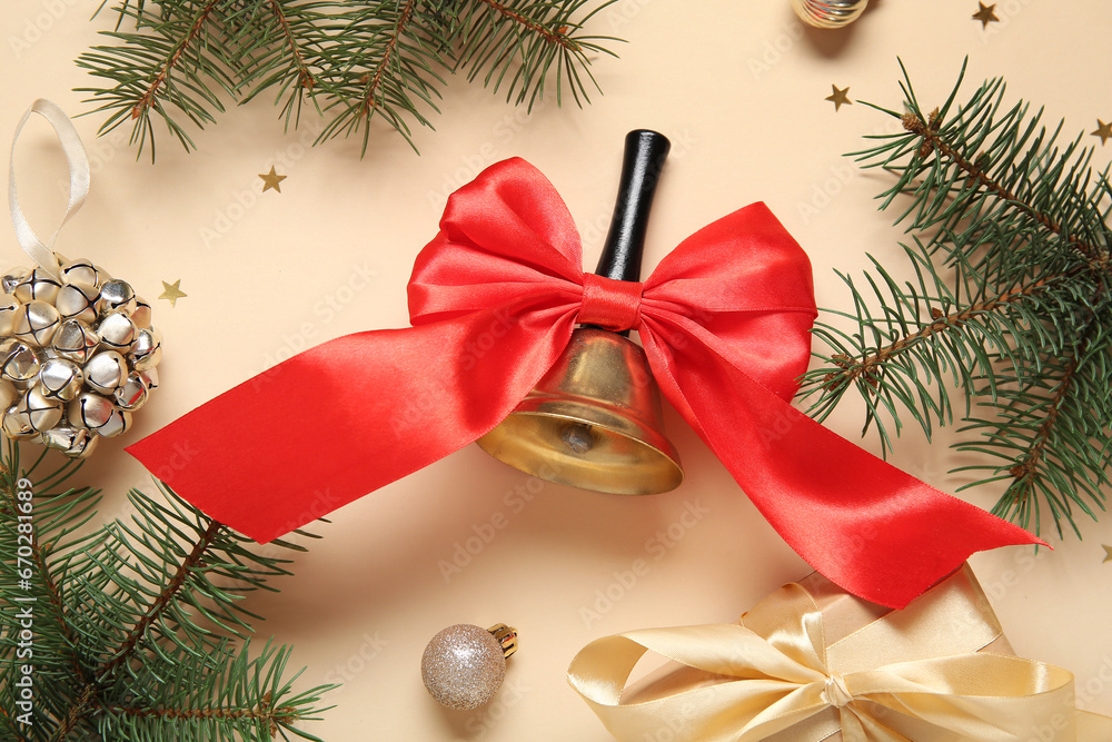 Christmas bell with fir branches and gift box on beige background