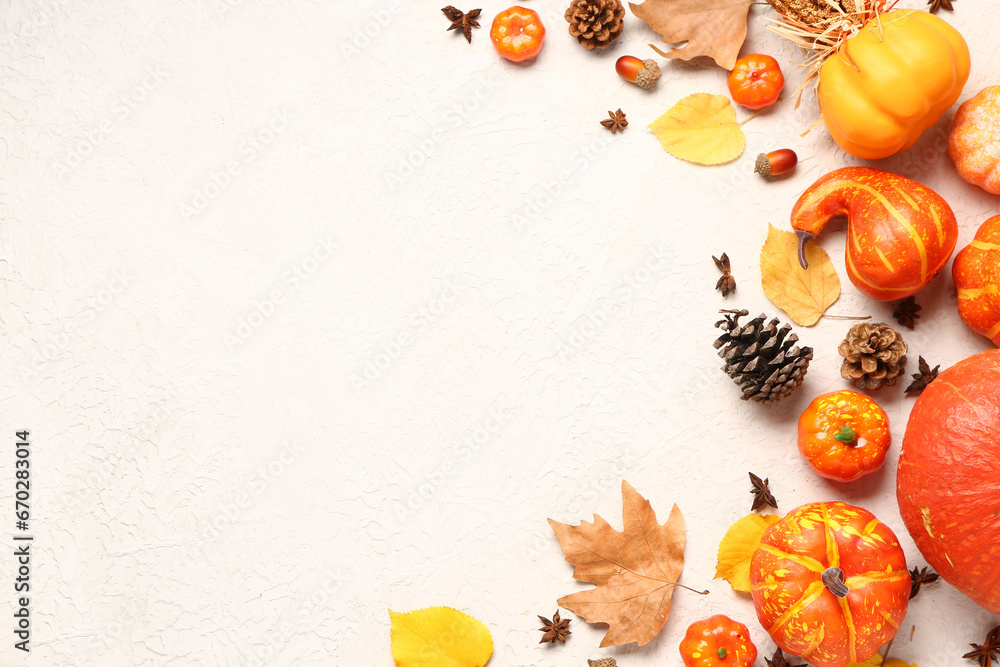 Autumn composition with ripe pumpkins, pine cones, spices and fallen leaves on light background