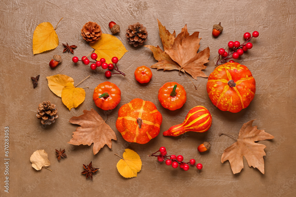 Autumn composition with ripe pumpkins, berries, spices and fallen leaves on brown background