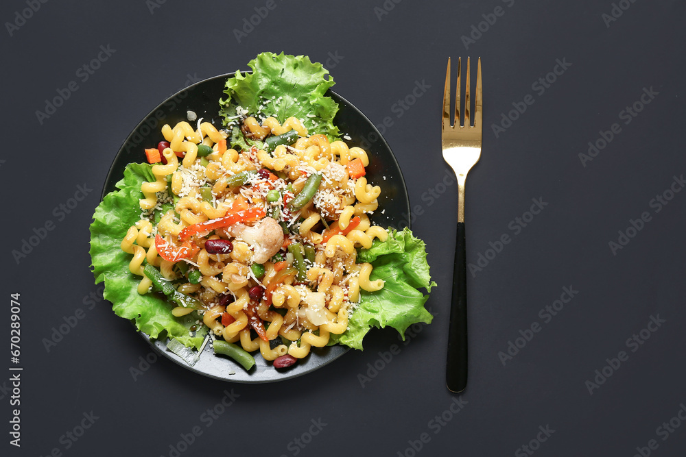 Plate with tasty pasta primavera on black background