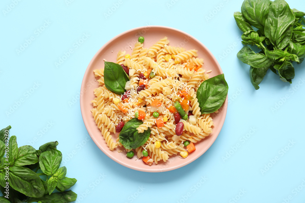 Plate with tasty pasta primavera on blue background