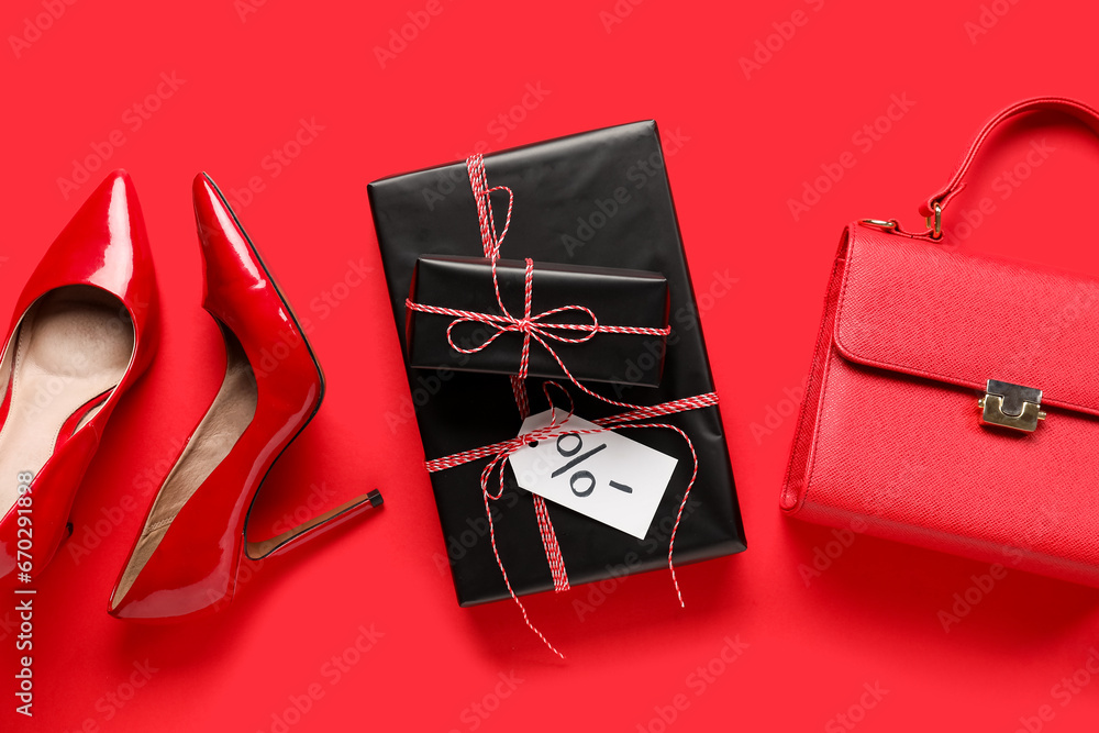 Stylish high heeled shoes, handbag and gift boxes on red background. Black Friday sale