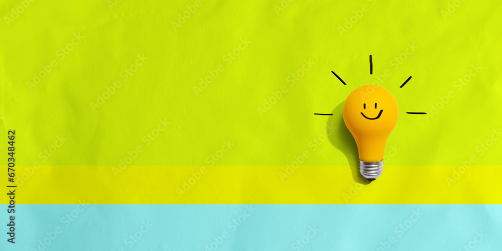 Yellow light bulb with happy face - flat lay