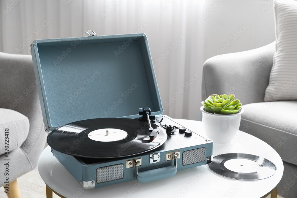 Record player with vinyl disk on table in living room