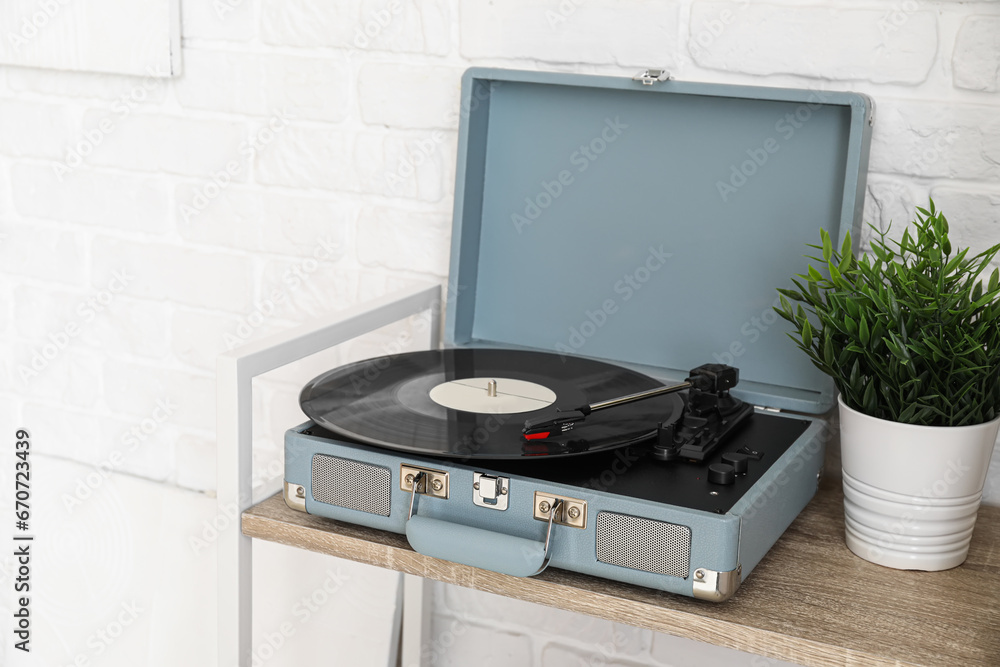 Record player with vinyl disk on wooden shelf