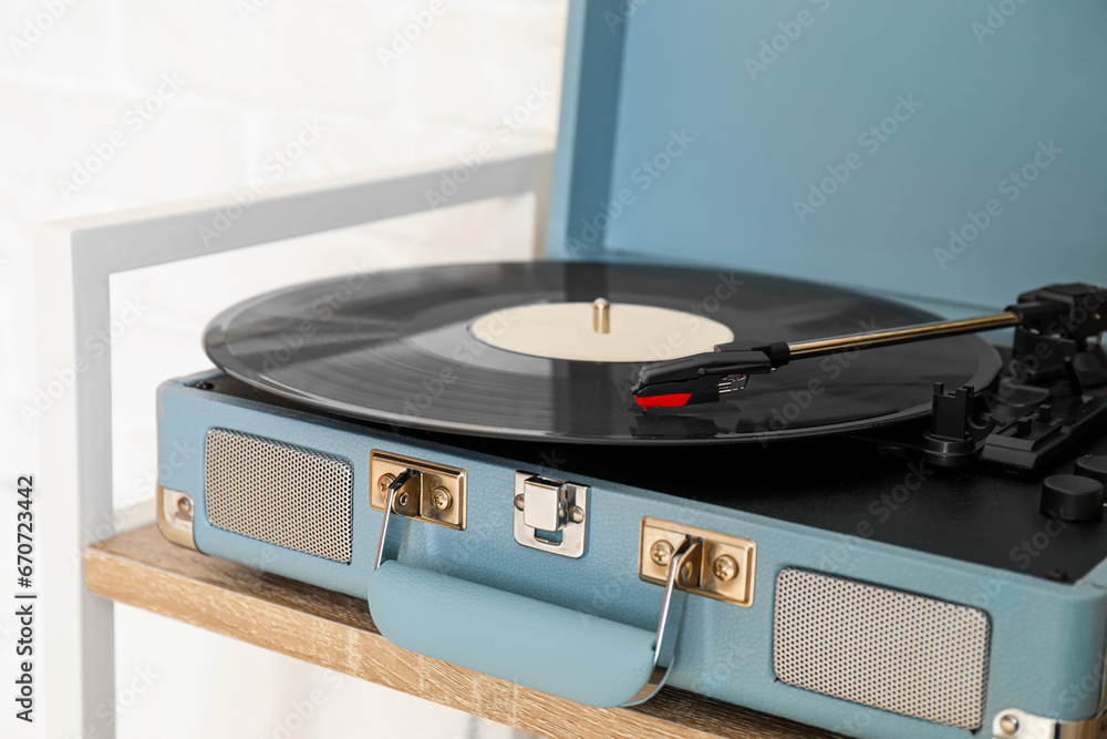 Record player with vinyl disk on wooden shelf