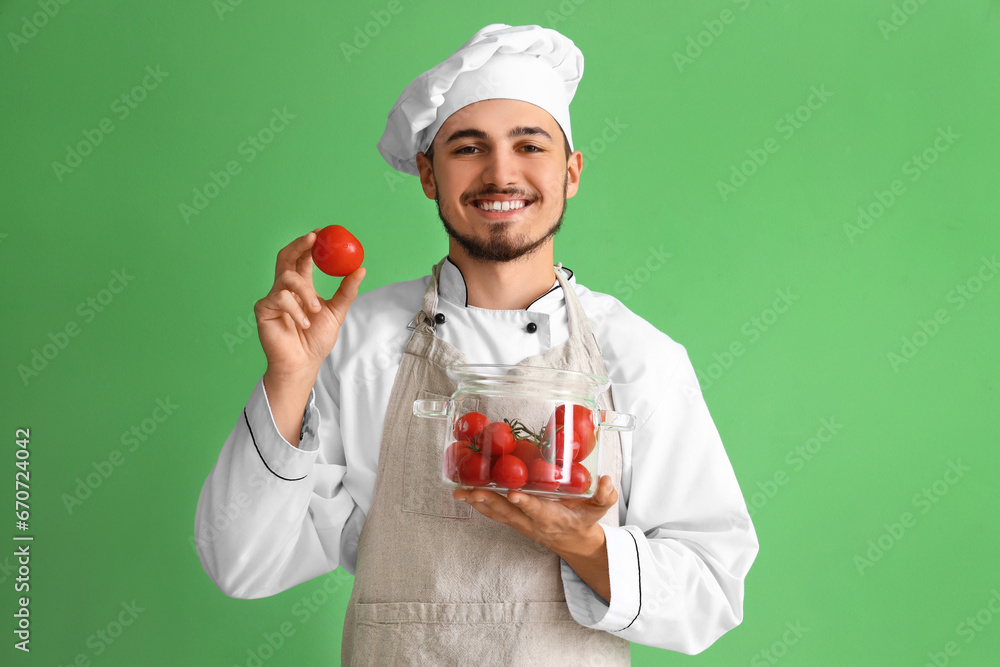 Male chef with fresh tomatoes on green background