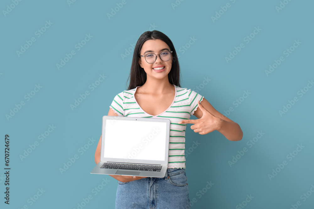 Happy female programmer pointing at laptop on blue background