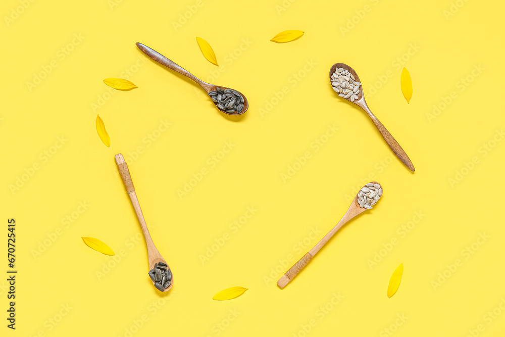 Frame made of sunflower petals and wooden spoons with seeds on yellow background