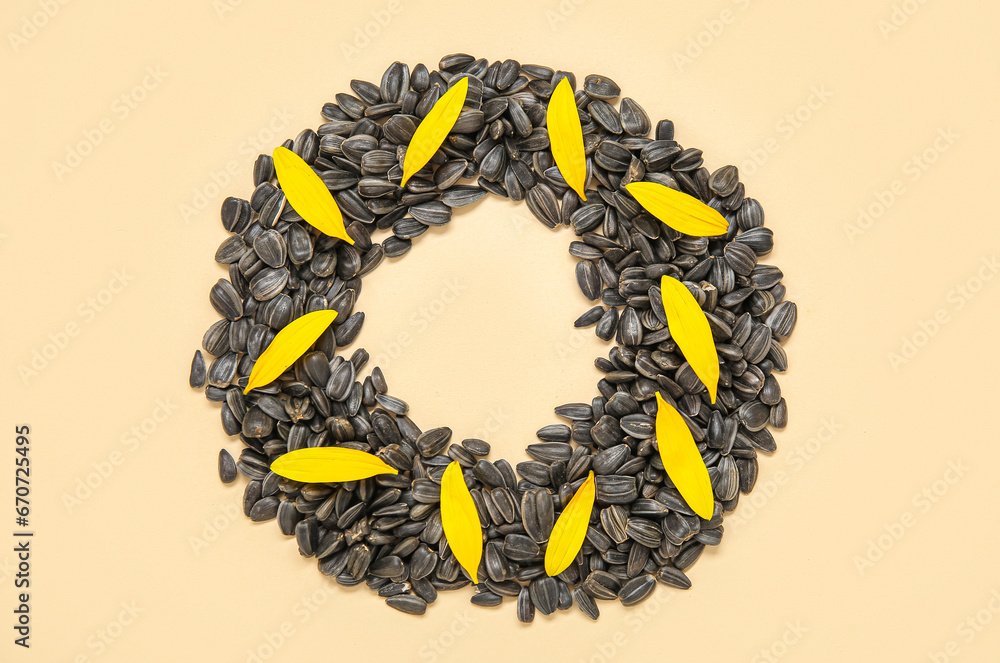 Frame made of sunflower petals and seeds on beige background