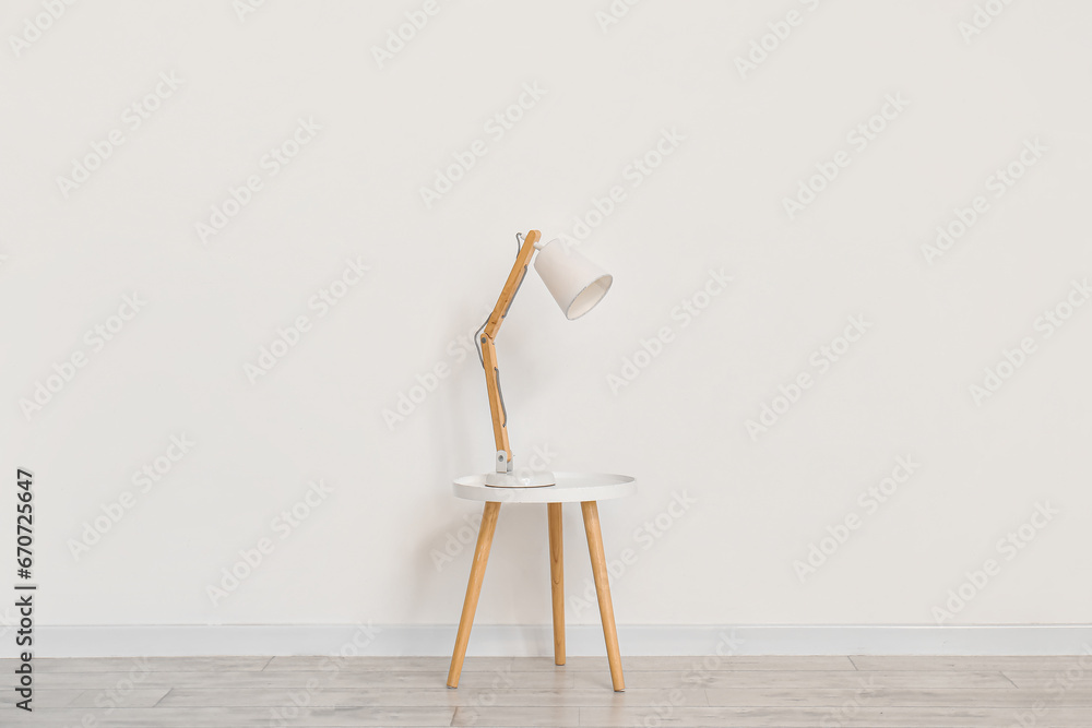 Desk lamp on small table near white wall