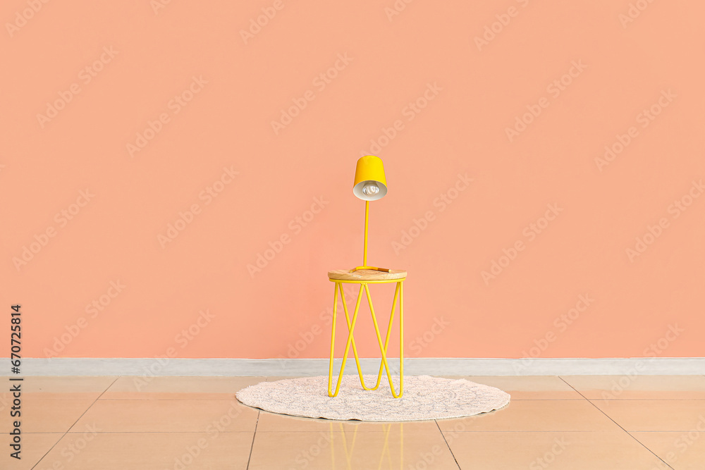 Yellow desk lamp on small table near pink wall