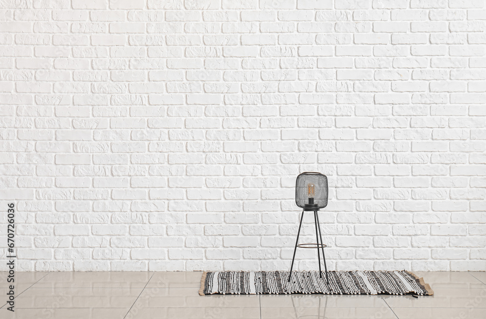 Small lamp on rug near white brick wall