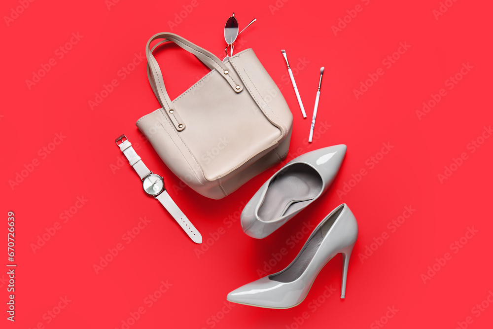 Composition with stylish female shoes, accessories and makeup brushes on red background