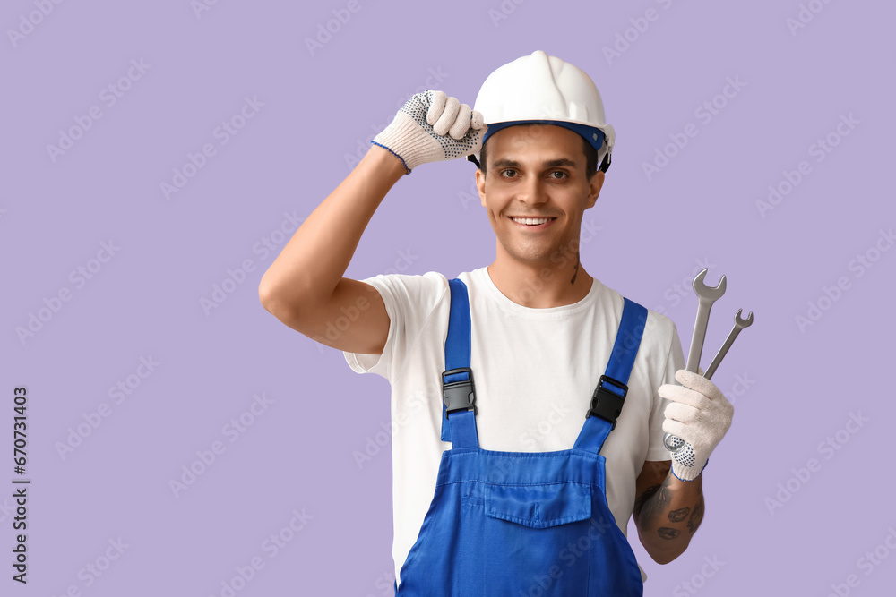 Male car mechanic with wrenches on lilac background