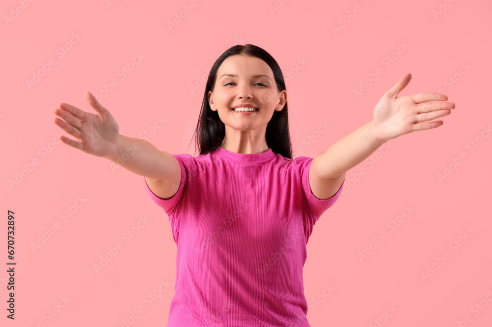 Young woman smiling on pink background