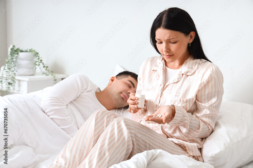 Young woman taking pills in bedroom