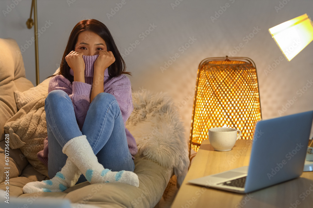 Frozen young Asian woman at home in evening