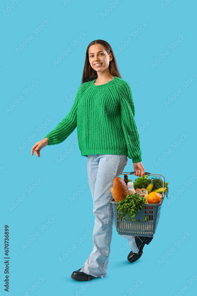 Young woman with shopping basket on blue background