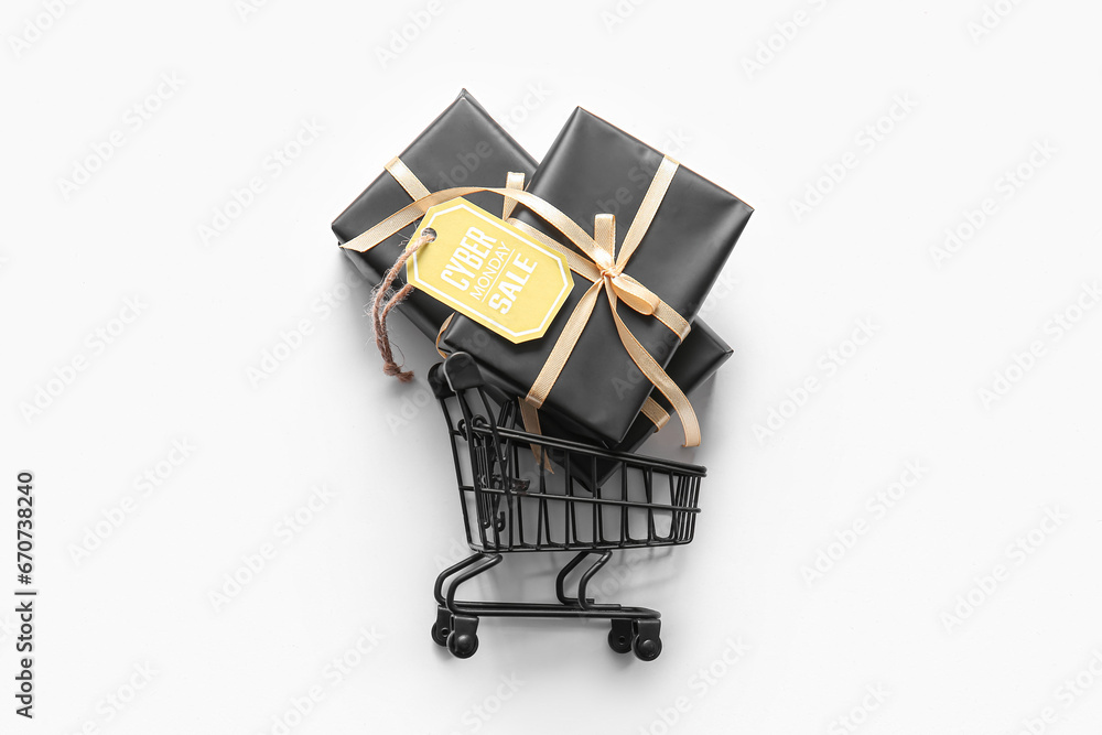 Small shopping cart, gift boxes and tag with text CYBER MONDAY SALE on light background