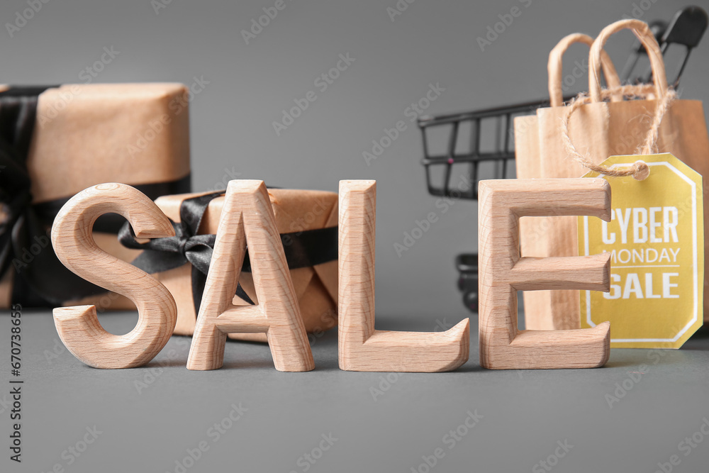 Word SALE made of wooden letters, gift boxes and shopping bag on grey background