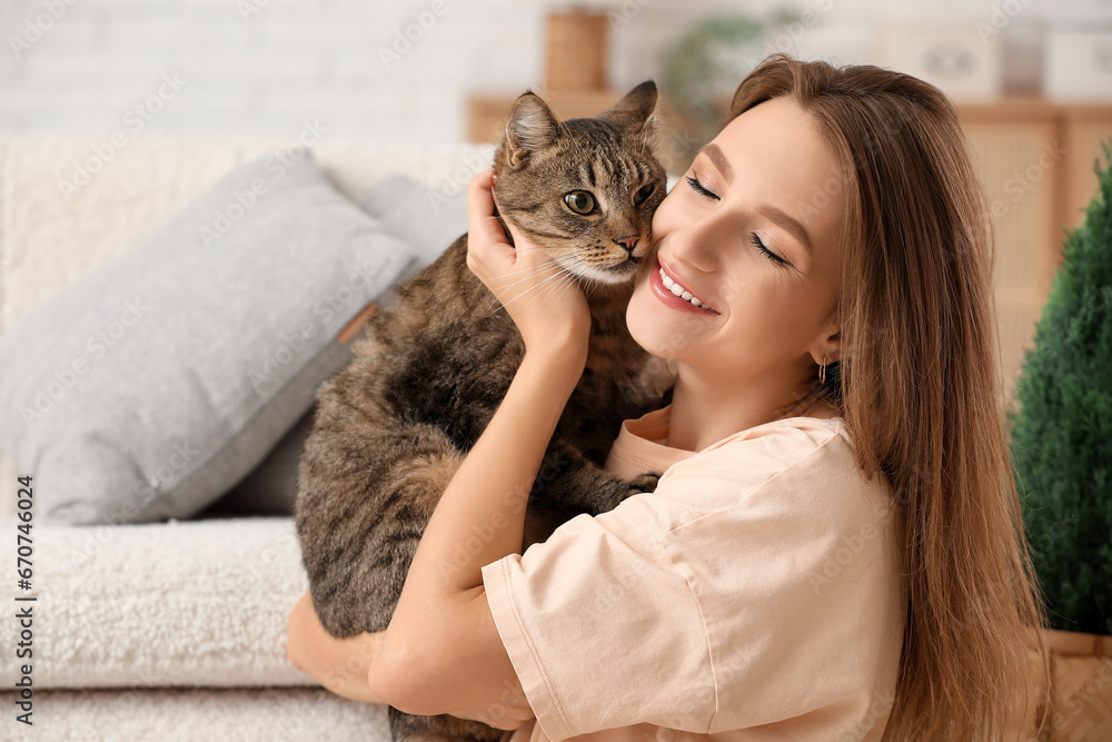 Pretty young woman with cute tabby cat at home, closeup