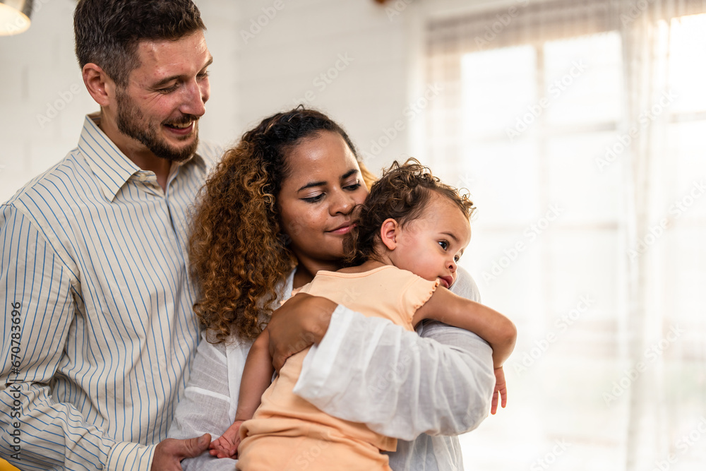 African American couple holding young baby girl in living room at home. 