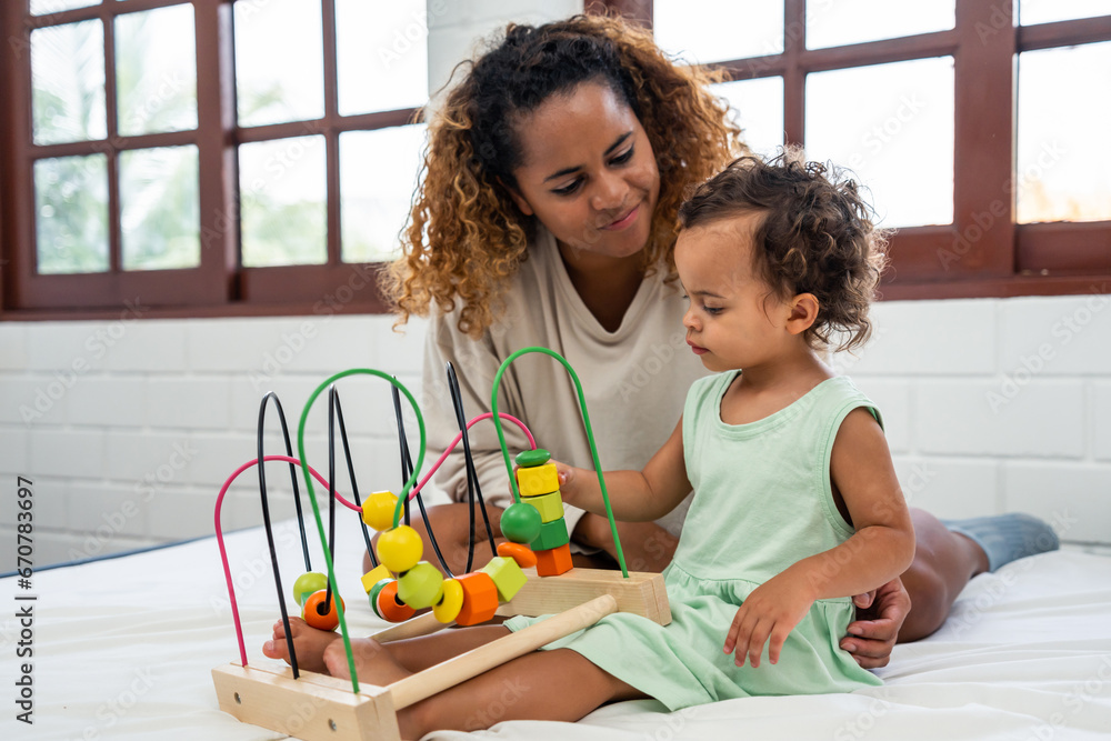 Caucasian mother spend leisure time with baby girl in bedroom at house.