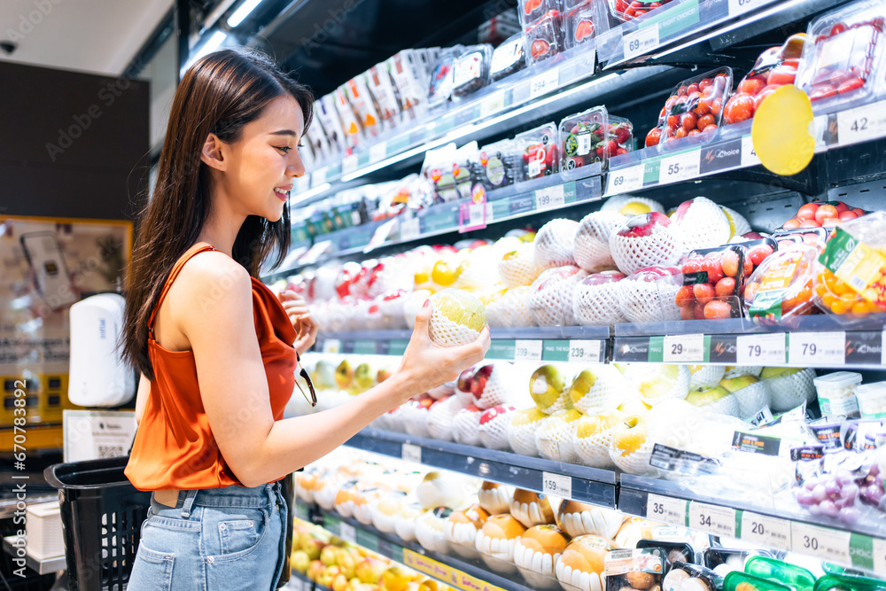 Asian young beautiful woman holding grocery basket walk in supermarket. 