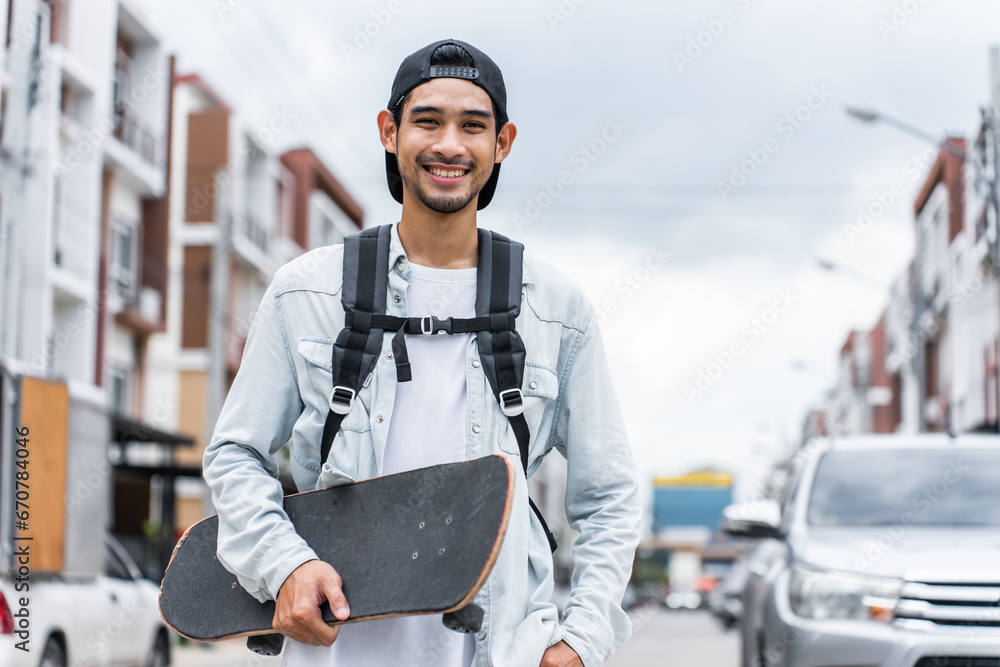 Asian young male holding surf skate board on street and look at camera. 