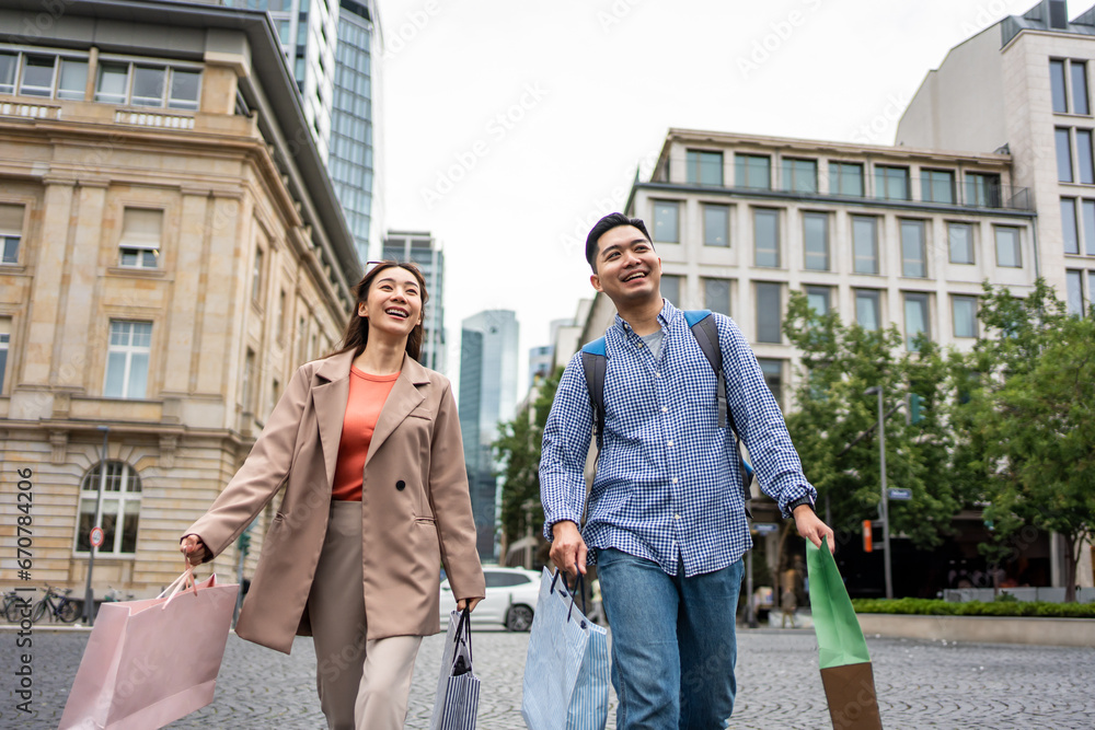 Asian young man and woman shopping goods outdoors in department store. 