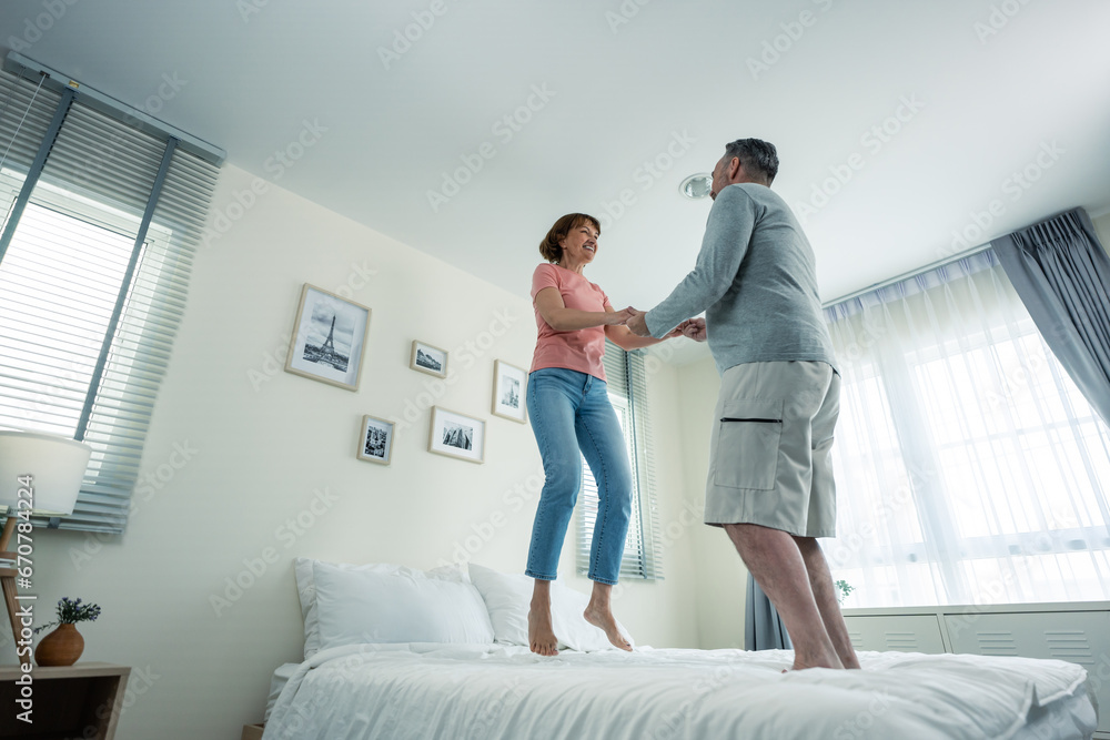 Caucasian senior couple dancing with music together in bedroom at home. 