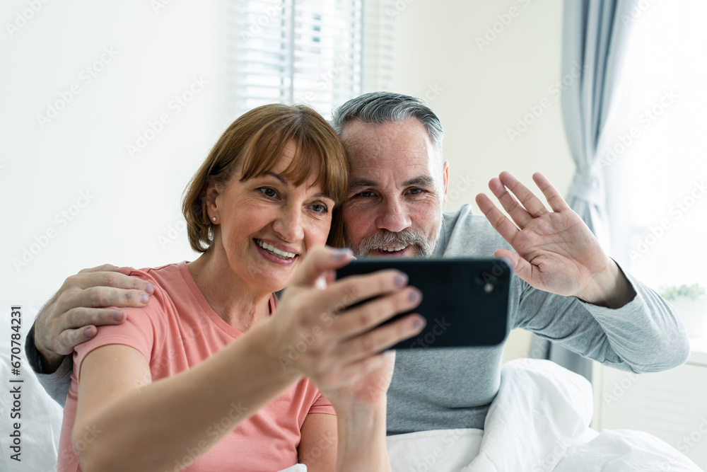 Caucasian senior couple video call with family in bedroom in house. 