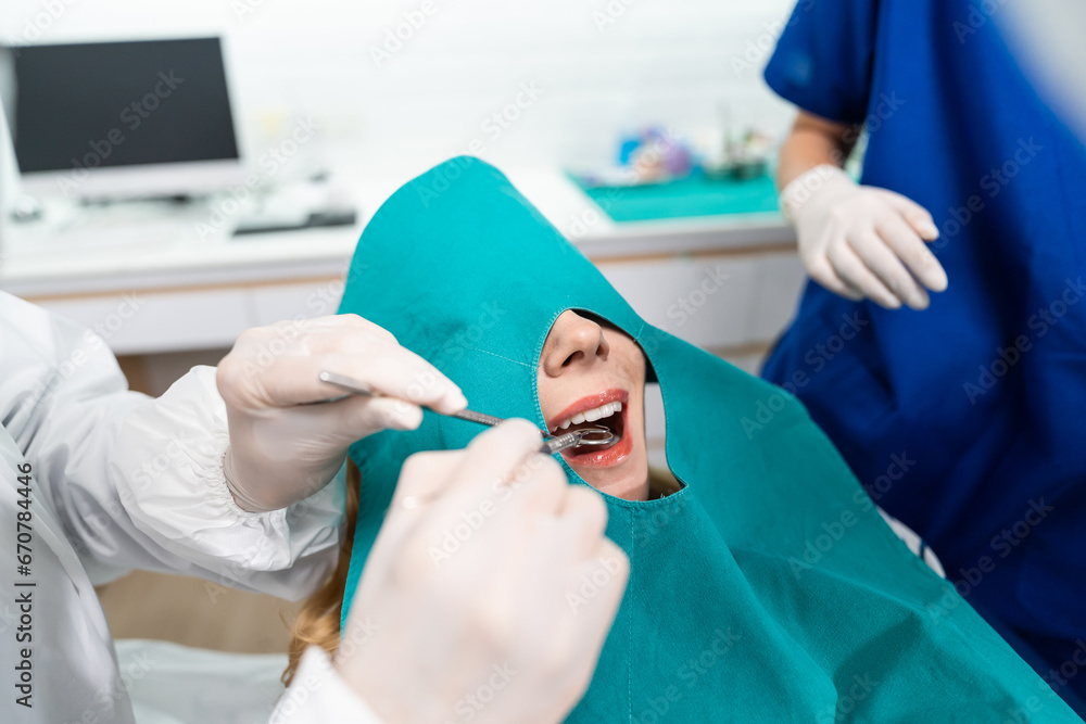 Female dentist examine tooth to Caucasian girl at dental health clinic. 