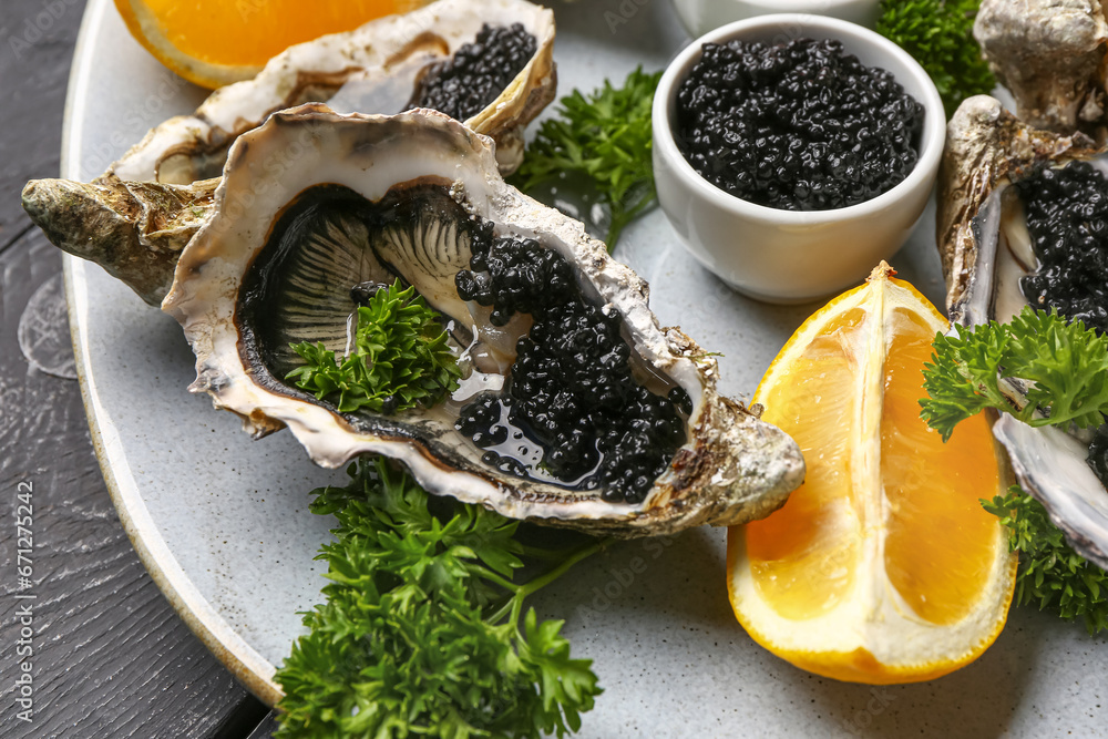 Plate of tasty oysters with lemon and black caviar on table