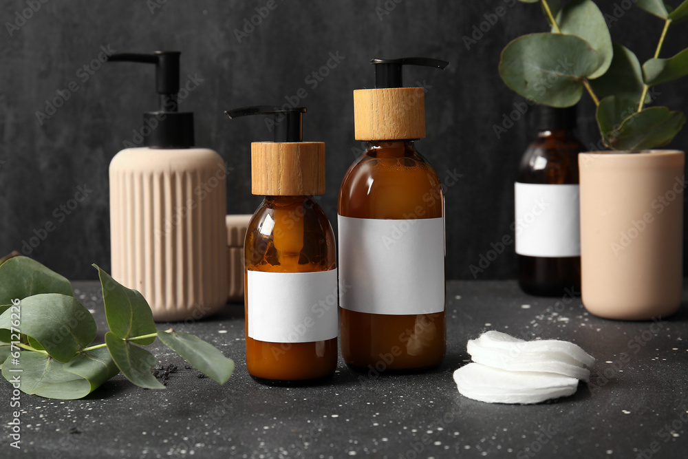 Bottles of shampoo and cotton pads on black background