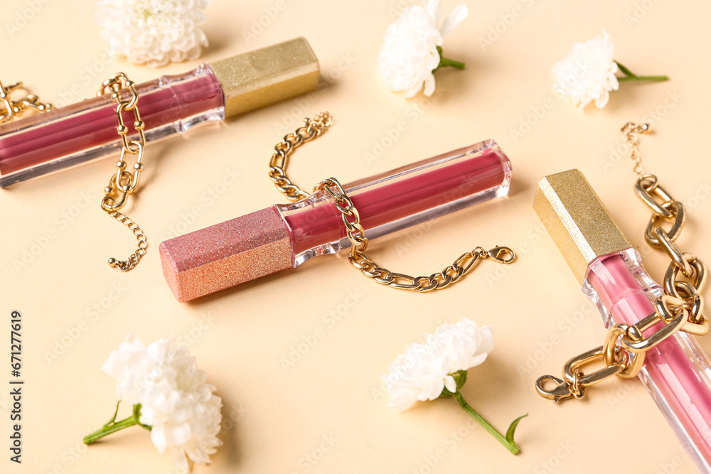 Composition with stylish lipsticks, jewelry and beautiful chrysanthemum flowers on beige background, closeup