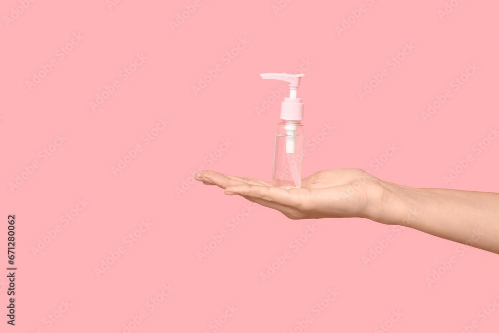 Young woman with bottle of cosmetic product on pink background