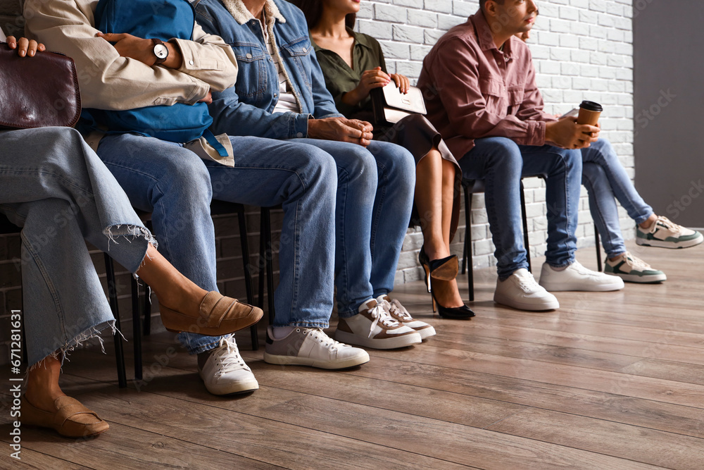 People waiting for their turn near grey brick wall