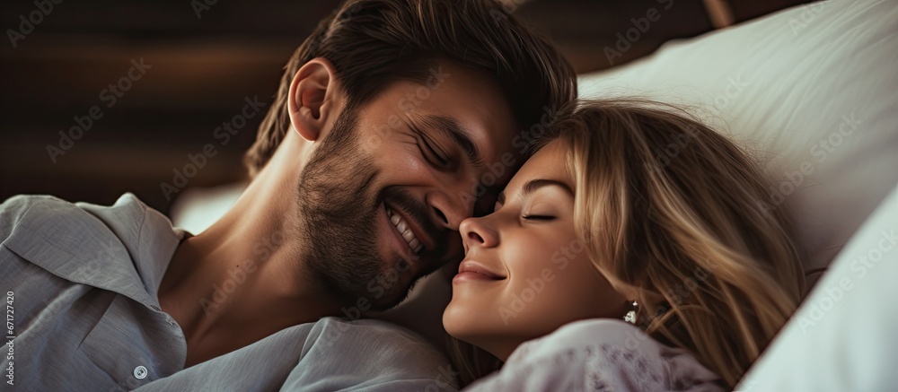 The couple filled with love and happiness wake up together in bed and radiate with beautiful smiles